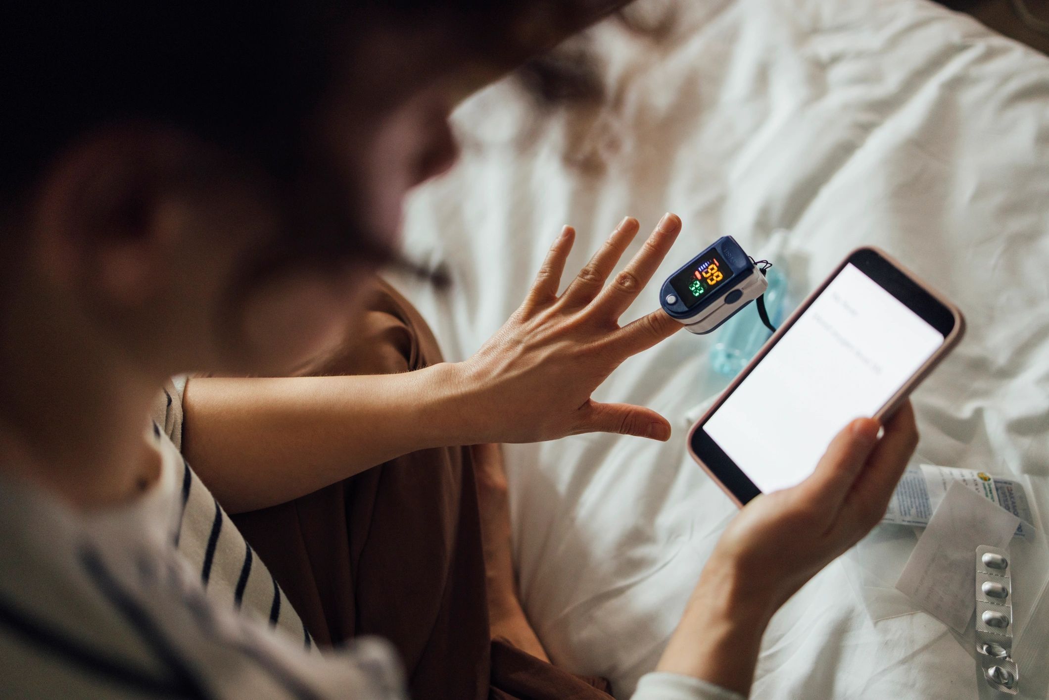 Patient using pulse oximeter and smartphone for home health monitoring